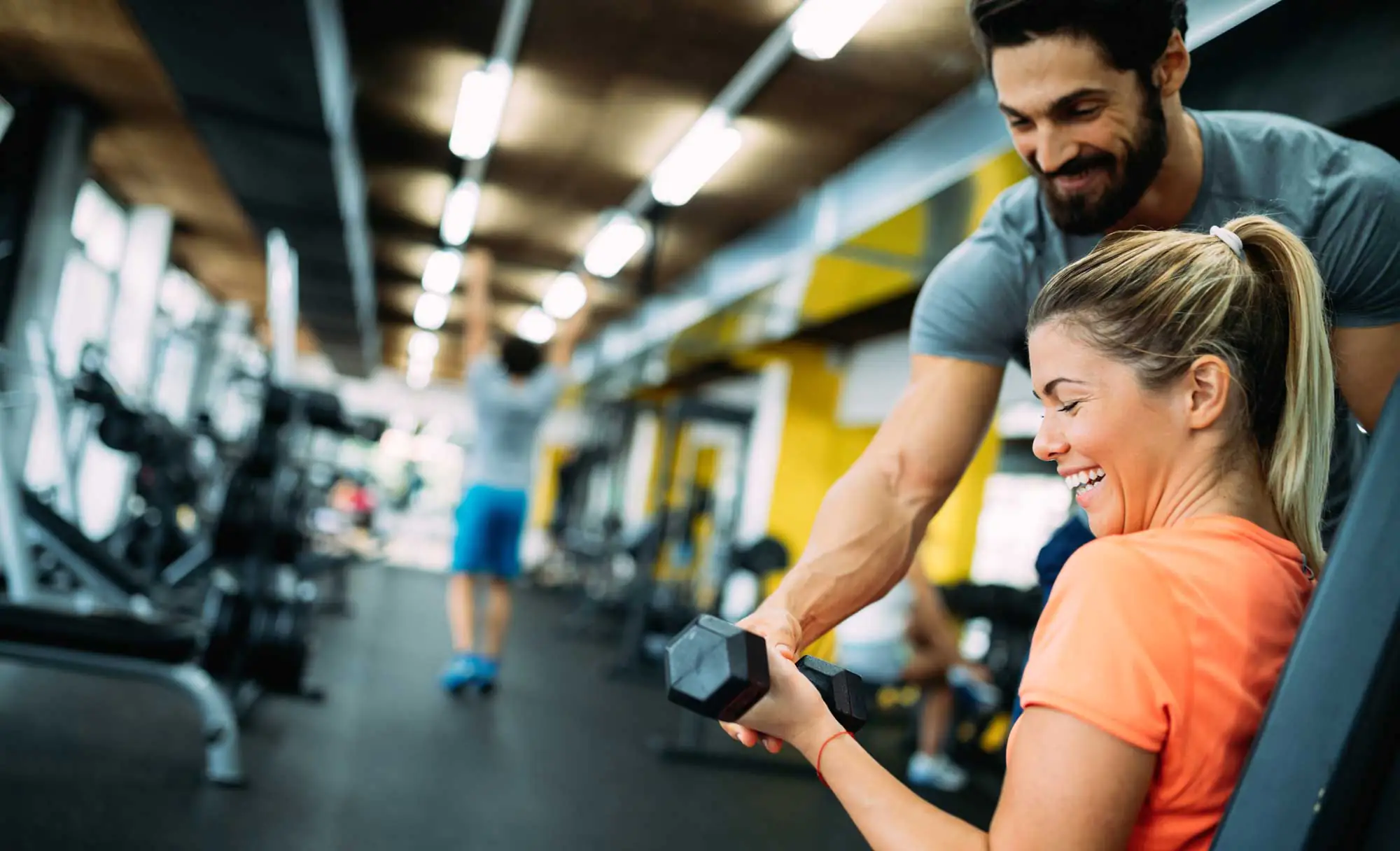 Young beautiful woman doing exercises with personal trainer in gym